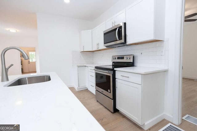 kitchen with a sink, appliances with stainless steel finishes, tasteful backsplash, and light countertops