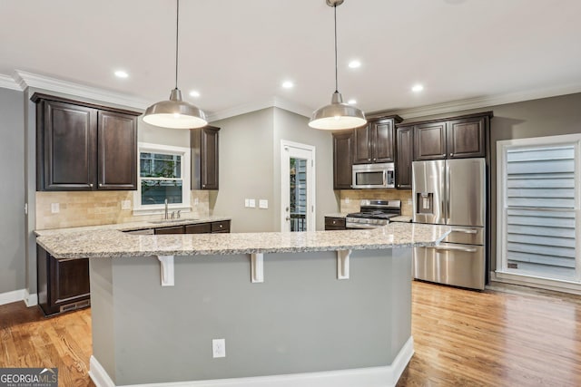 737 St Charles Ave NE, Atlanta, GA 30306 - kitchen with stainless steel appliances, a sink, dark brown cabinetry, ornamental molding, and a breakfast bar