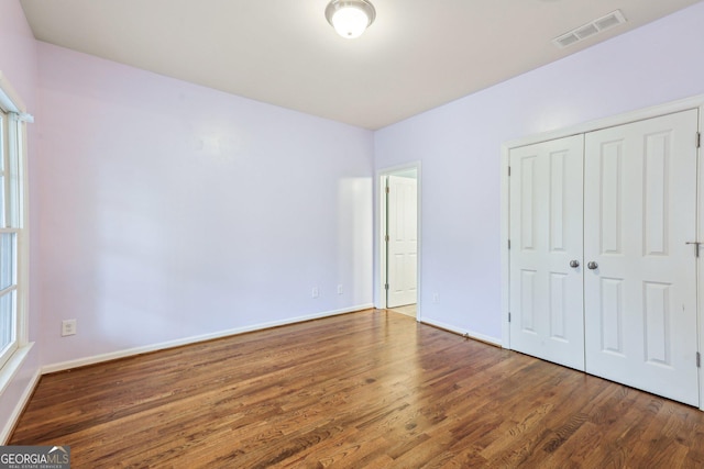 737 St Charles Ave NE, Atlanta, GA 30306 - unfurnished bedroom with wood finished floors, a closet, and baseboards