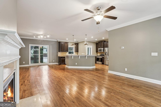 737 St Charles Ave NE, Atlanta, GA 30306 - unfurnished living room with a lit fireplace, crown molding, wood finished floors, ceiling fan, and baseboards