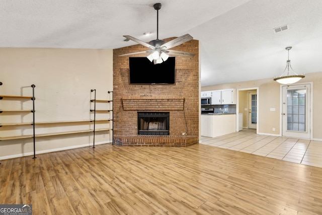 unfurnished living room with a textured ceiling, a ceiling fan, light wood-style flooring, and visible vents