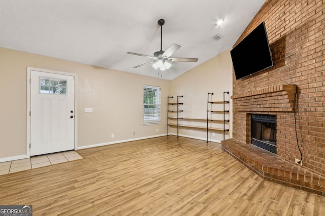 unfurnished living room with visible vents, lofted ceiling, wood finished floors, a fireplace, and a ceiling fan