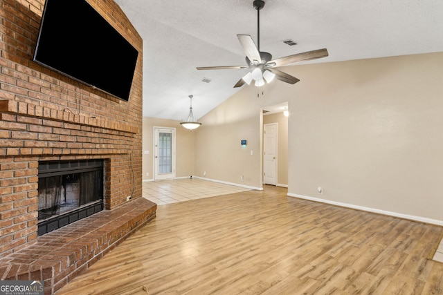 unfurnished living room featuring a ceiling fan, a fireplace, vaulted ceiling, baseboards, and light wood-style floors
