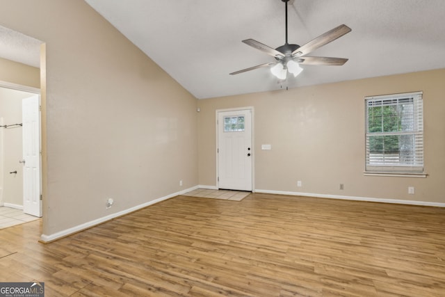 empty room featuring ceiling fan, baseboards, lofted ceiling, and light wood-style floors