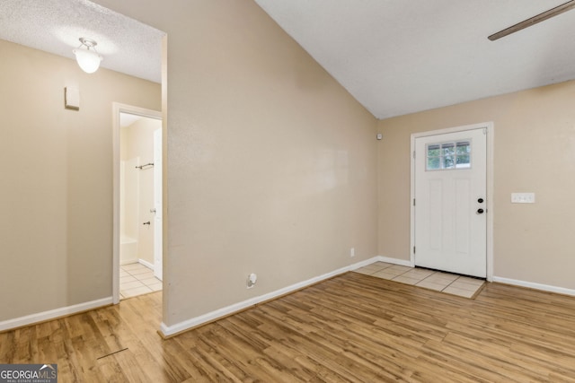 entrance foyer featuring baseboards, wood finished floors, and lofted ceiling
