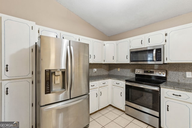 kitchen with white cabinets, stainless steel appliances, vaulted ceiling, and decorative backsplash