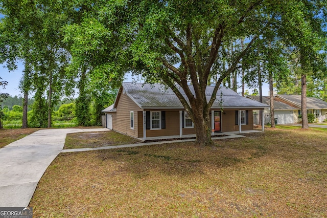 view of front of house with a porch, driveway, a front yard, and metal roof