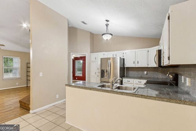 kitchen featuring white cabinets, appliances with stainless steel finishes, a sink, a peninsula, and decorative backsplash