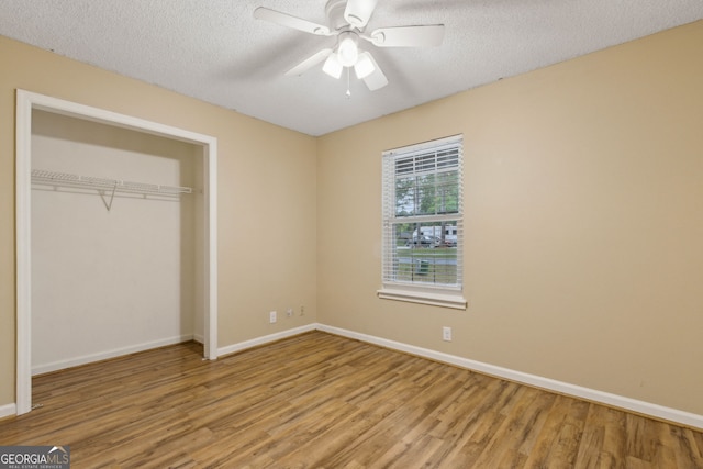 unfurnished bedroom with a closet, wood finished floors, baseboards, a textured ceiling, and a ceiling fan