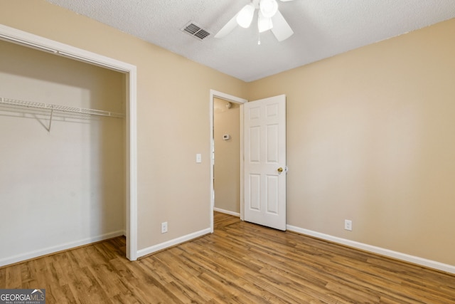 unfurnished bedroom featuring visible vents, baseboards, wood finished floors, and a closet