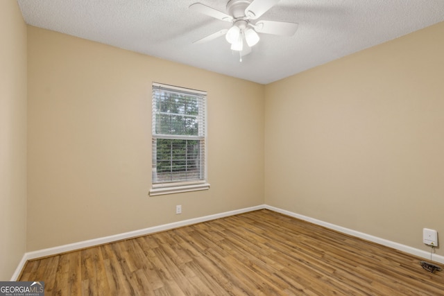 empty room with baseboards, a ceiling fan, a textured ceiling, and wood finished floors