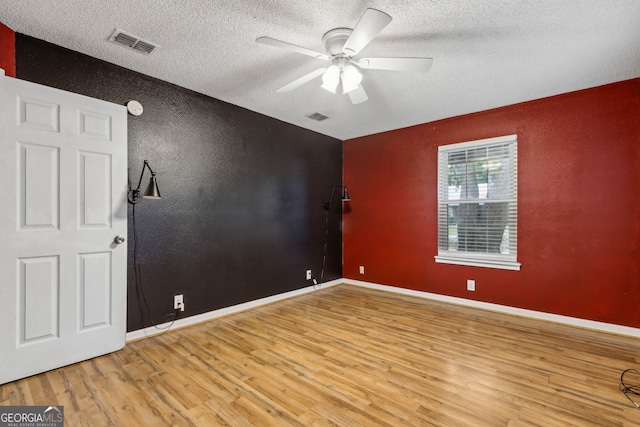 empty room featuring a textured ceiling, ceiling fan, light wood-style flooring, and visible vents