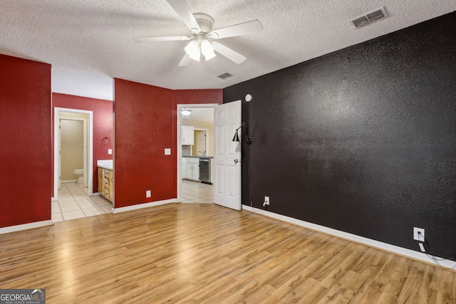 unfurnished bedroom featuring baseboards, light wood-type flooring, a textured ceiling, and visible vents