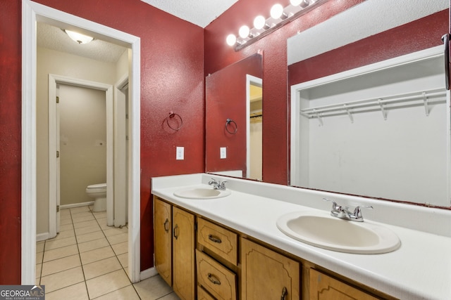 full bath featuring double vanity, toilet, a sink, and tile patterned flooring