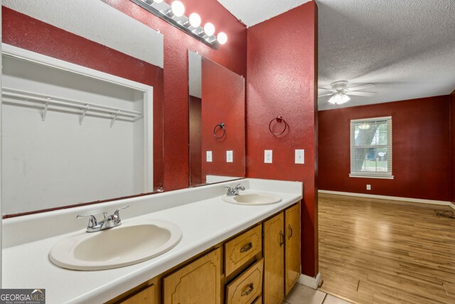 full bath featuring double vanity, a sink, a textured ceiling, and a ceiling fan