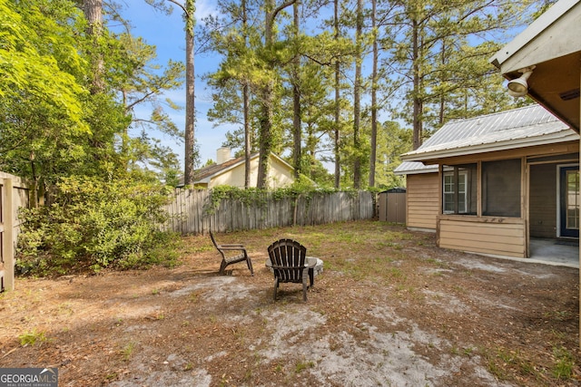 view of yard with a fenced backyard, an outdoor fire pit, a storage shed, and an outbuilding