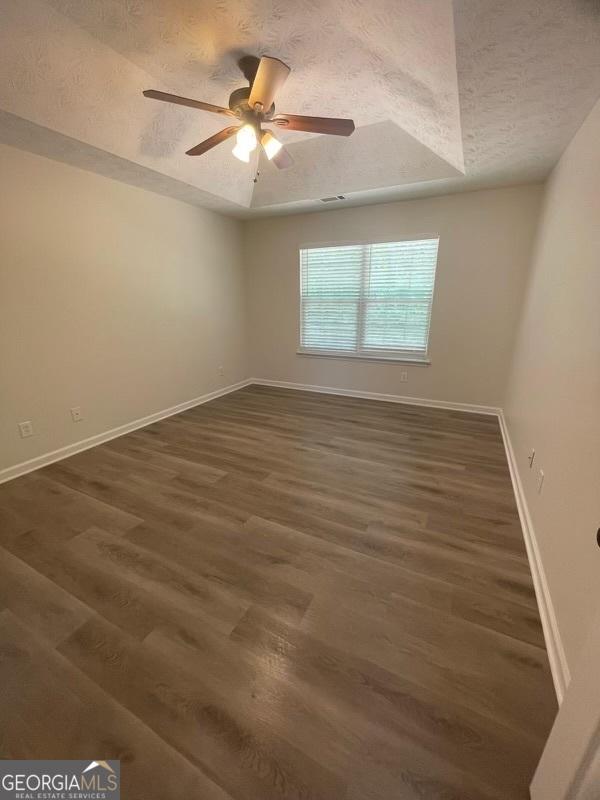 spare room with baseboards, a textured ceiling, and wood finished floors