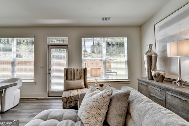 living room with visible vents, baseboards, wood finished floors, and a healthy amount of sunlight