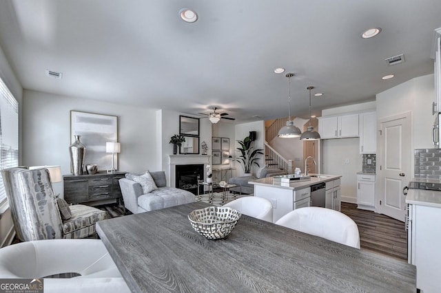 dining space with stairway, a fireplace, a ceiling fan, and visible vents