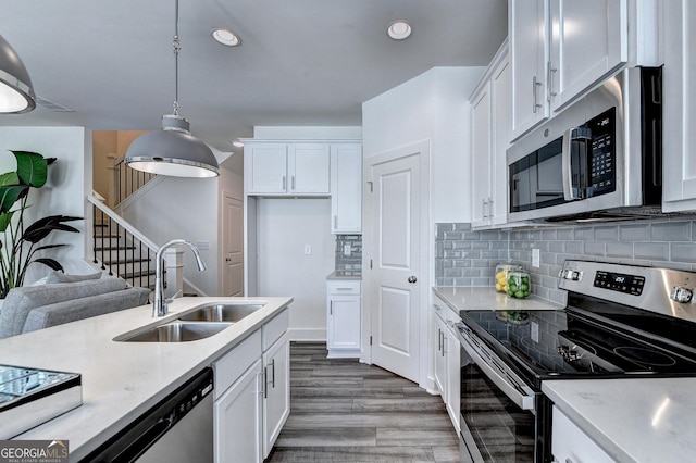 kitchen featuring a sink, appliances with stainless steel finishes, white cabinetry, and light countertops