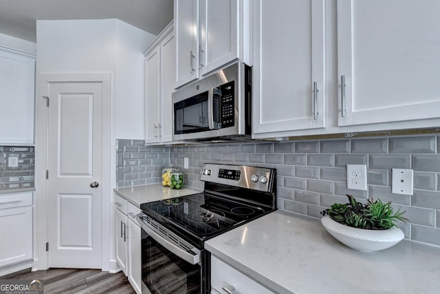 kitchen with white cabinetry, appliances with stainless steel finishes, wood finished floors, and tasteful backsplash