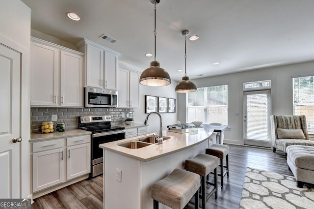 kitchen featuring appliances with stainless steel finishes, a sink, light countertops, white cabinetry, and wood finished floors
