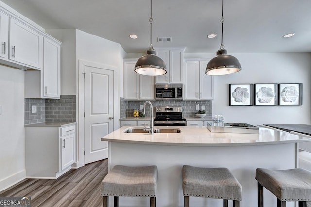 kitchen with a sink, white cabinetry, wood finished floors, and stainless steel appliances