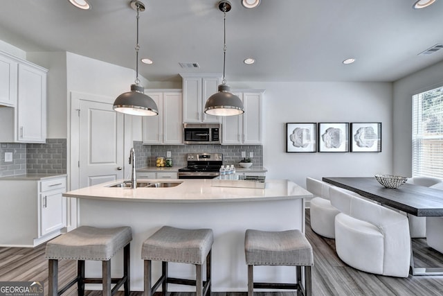 kitchen with a sink, stainless steel appliances, wood finished floors, and visible vents