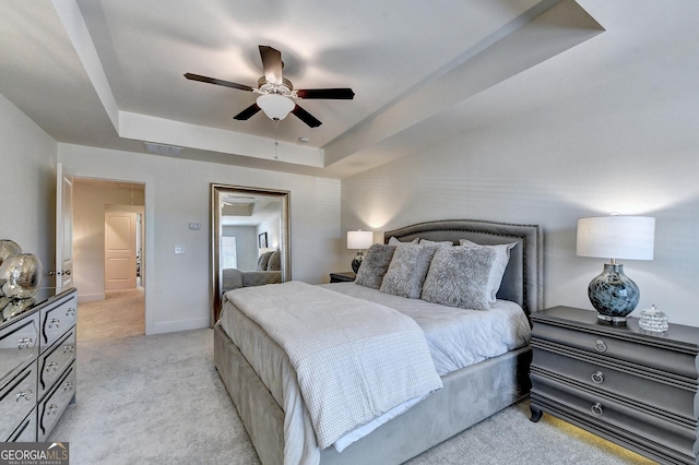 bedroom featuring ceiling fan, light colored carpet, baseboards, and a raised ceiling