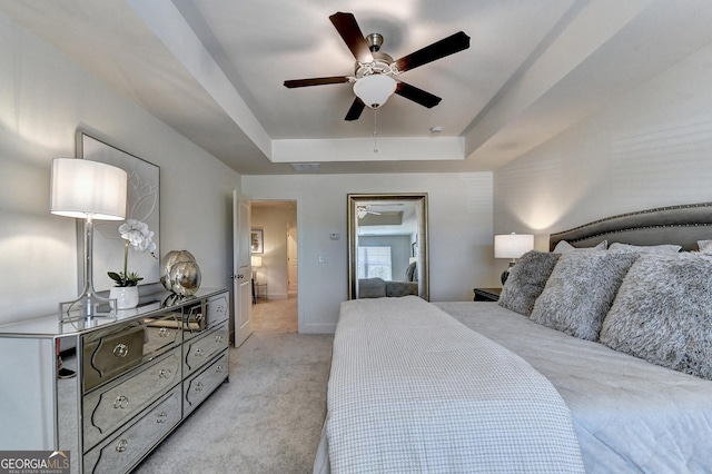 bedroom featuring baseboards, a raised ceiling, ceiling fan, and light carpet