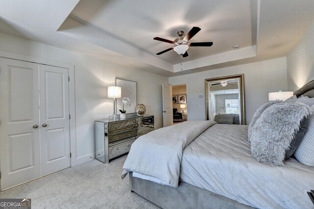 bedroom featuring a raised ceiling, baseboards, ceiling fan, and light colored carpet