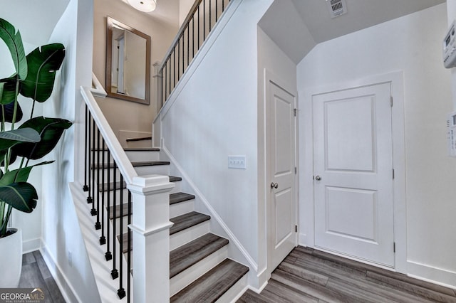 stairway featuring baseboards, wood finished floors, and visible vents