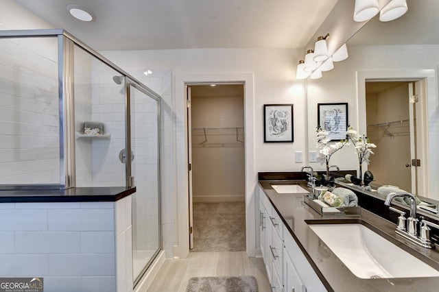 bathroom with a sink, a stall shower, double vanity, and a spacious closet