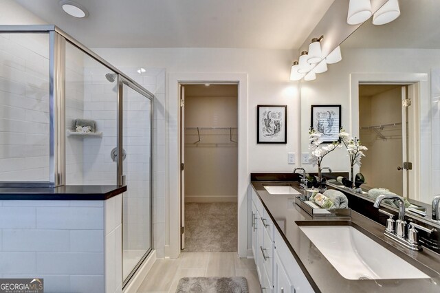 full bathroom with a sink, a shower stall, and double vanity