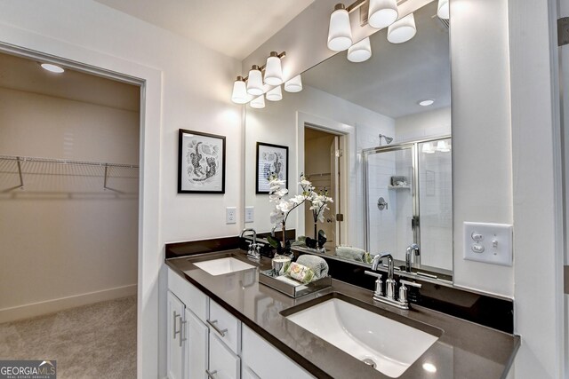 full bathroom with double vanity, a sink, a stall shower, and a spacious closet