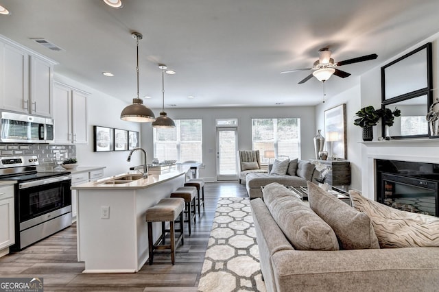 kitchen featuring appliances with stainless steel finishes, a sink, a breakfast bar area, an island with sink, and open floor plan