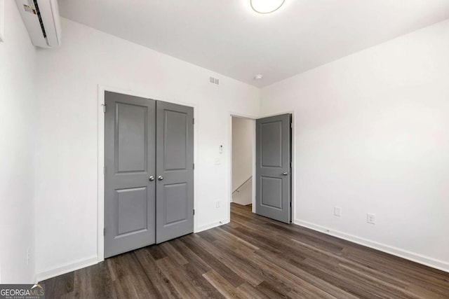 585 Ira St SW, Atlanta, GA 30312 - unfurnished bedroom with baseboards, dark wood finished floors, a wall unit AC, and visible vents