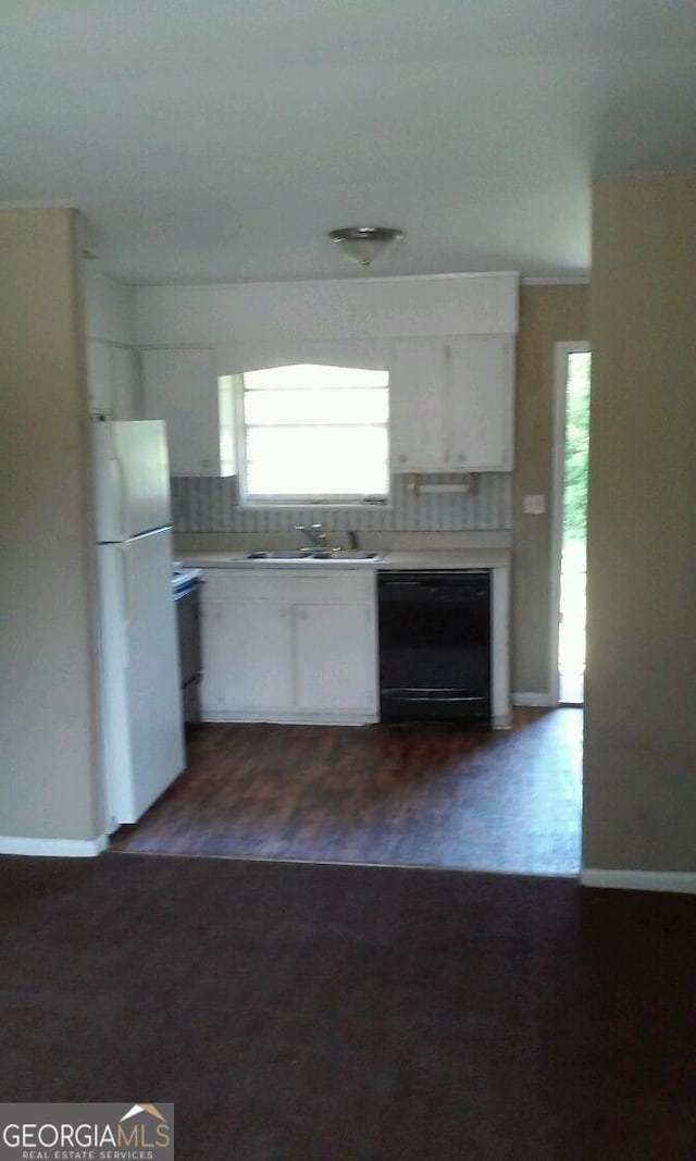 kitchen featuring freestanding refrigerator, a sink, dishwasher, and white cabinets