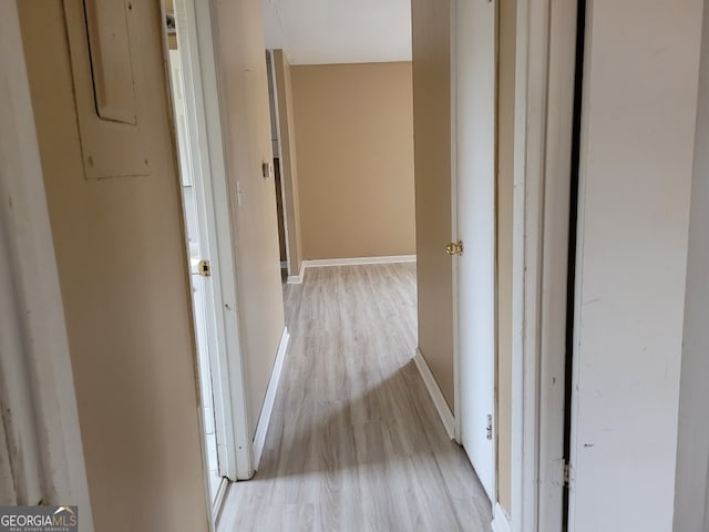 hall with light wood-style floors and baseboards
