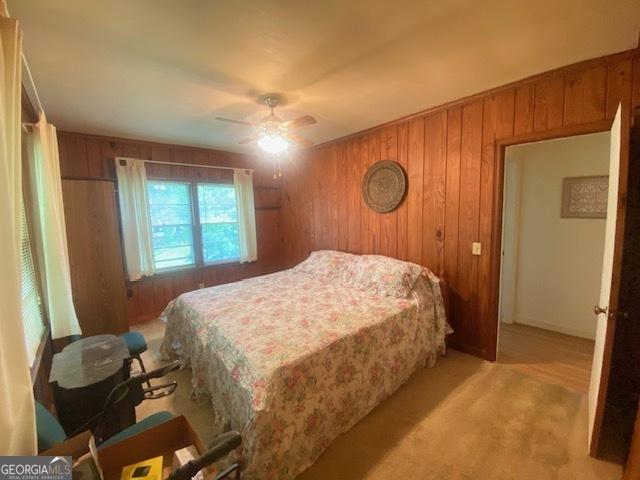 719 N 18th St, Lanett, AL 36863 - bedroom with wood walls, light colored carpet, and a ceiling fan