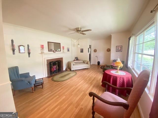 719 N 18th St, Lanett, AL 36863 - living area featuring wood finished floors, a ceiling fan, and a fireplace