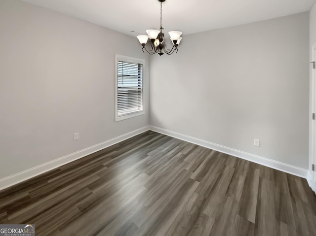 empty room with an inviting chandelier, baseboards, and dark wood-style flooring