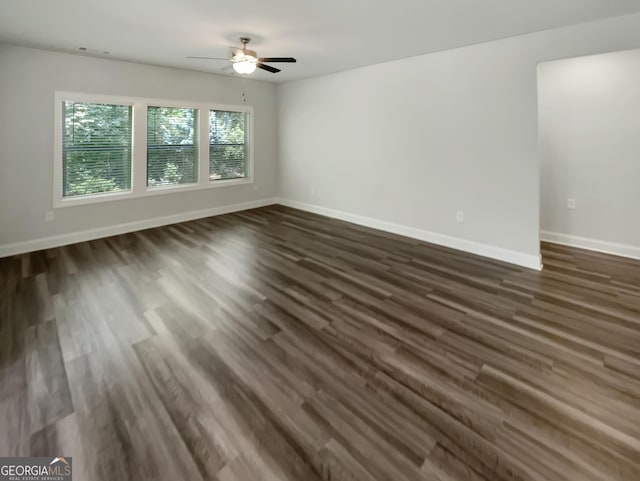 spare room with baseboards, dark wood finished floors, and ceiling fan
