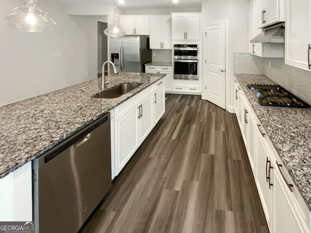 kitchen with white cabinets, appliances with stainless steel finishes, a sink, under cabinet range hood, and dark wood-style floors