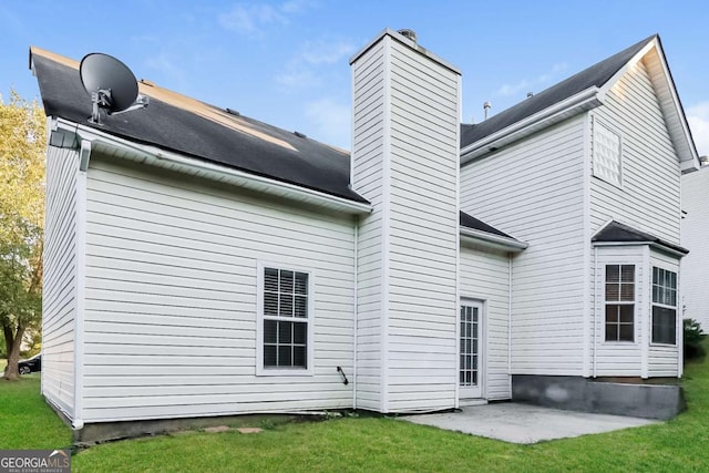 rear view of house with a lawn, a patio, and a chimney