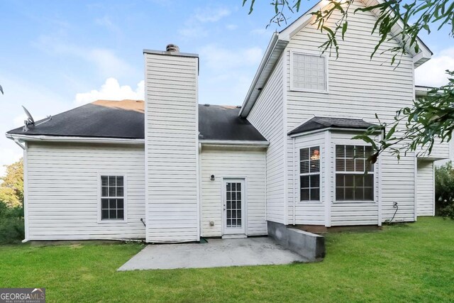 rear view of house featuring a patio, a lawn, and a chimney