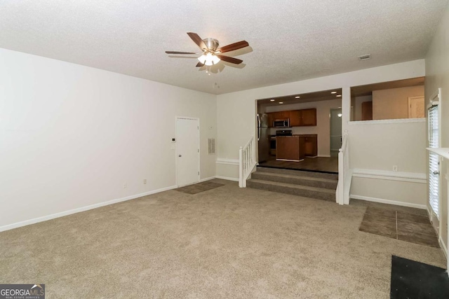unfurnished living room featuring carpet flooring, a textured ceiling, and ceiling fan