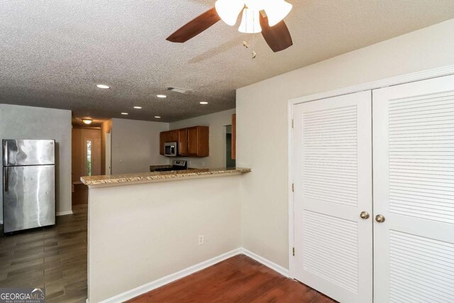 kitchen with ceiling fan, appliances with stainless steel finishes, a textured ceiling, recessed lighting, and dark wood-type flooring