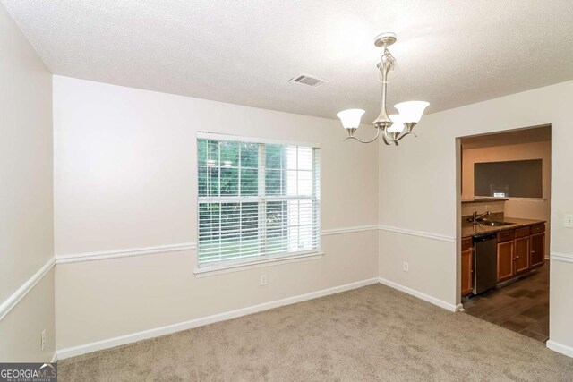 carpeted empty room with visible vents, a sink, baseboards, and a notable chandelier