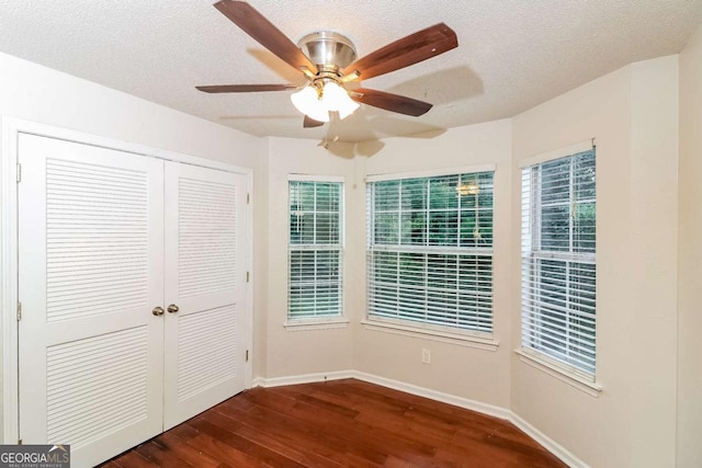 unfurnished bedroom featuring ceiling fan, a textured ceiling, baseboards, dark wood-type flooring, and a closet